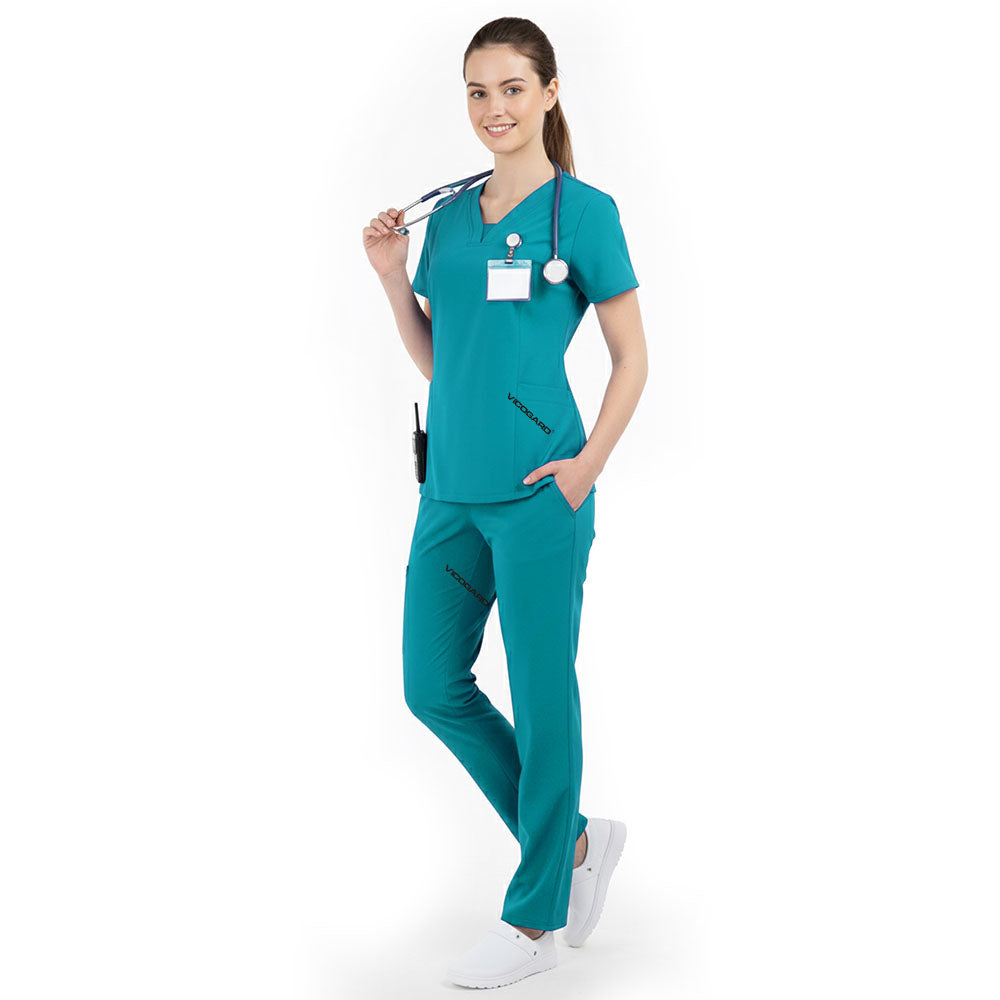 Model placing hand in pocket of Teal scrub pants, showing functionality