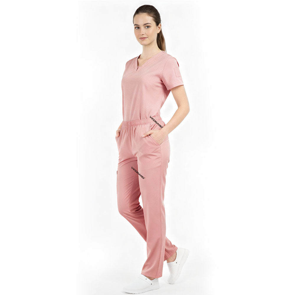 Model placing hand in pocket of Pink scrub pants, showing functionality