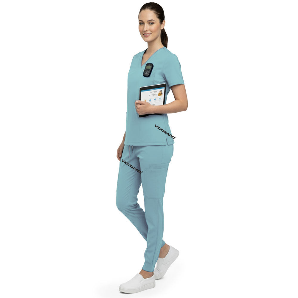 Side profile of nursing student holding clipboard wearing Ceil Blue rayon scrubs showing athletic fit