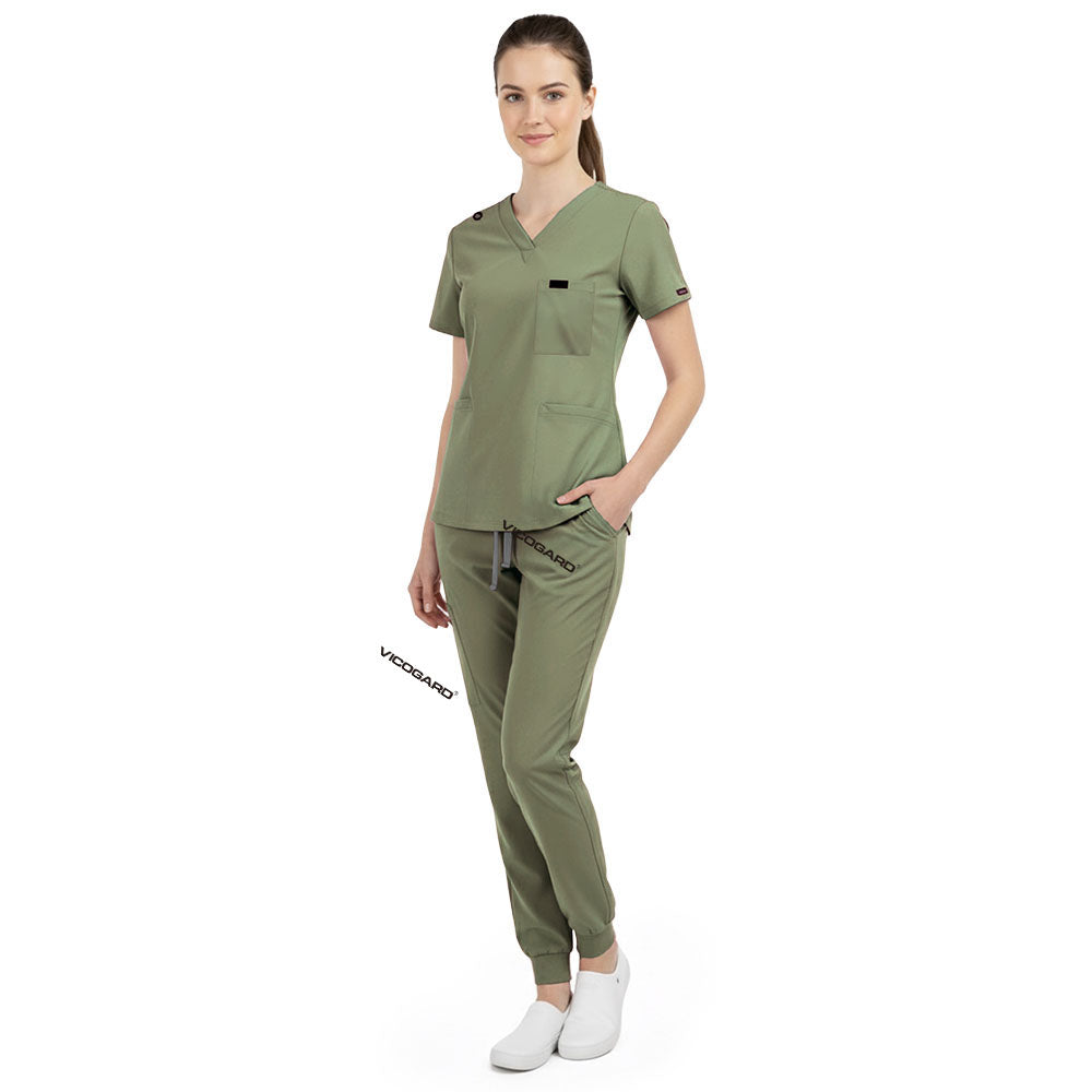 Side view of model using pockets on Fruit Green scrub pants, showing storage depth