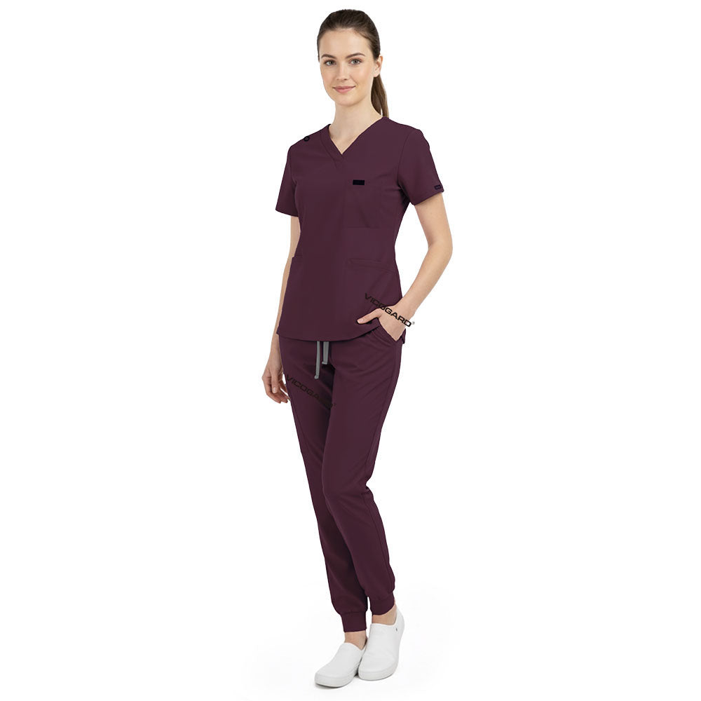 Side view of model using pockets on Burgundy scrub pants, showing storage depth