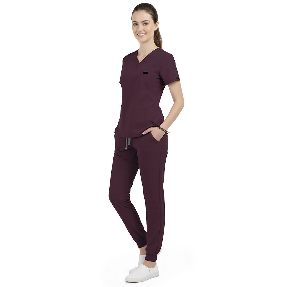 Front view of model with both hands in pockets, demonstrating relaxed fit of Burgundy scrubs