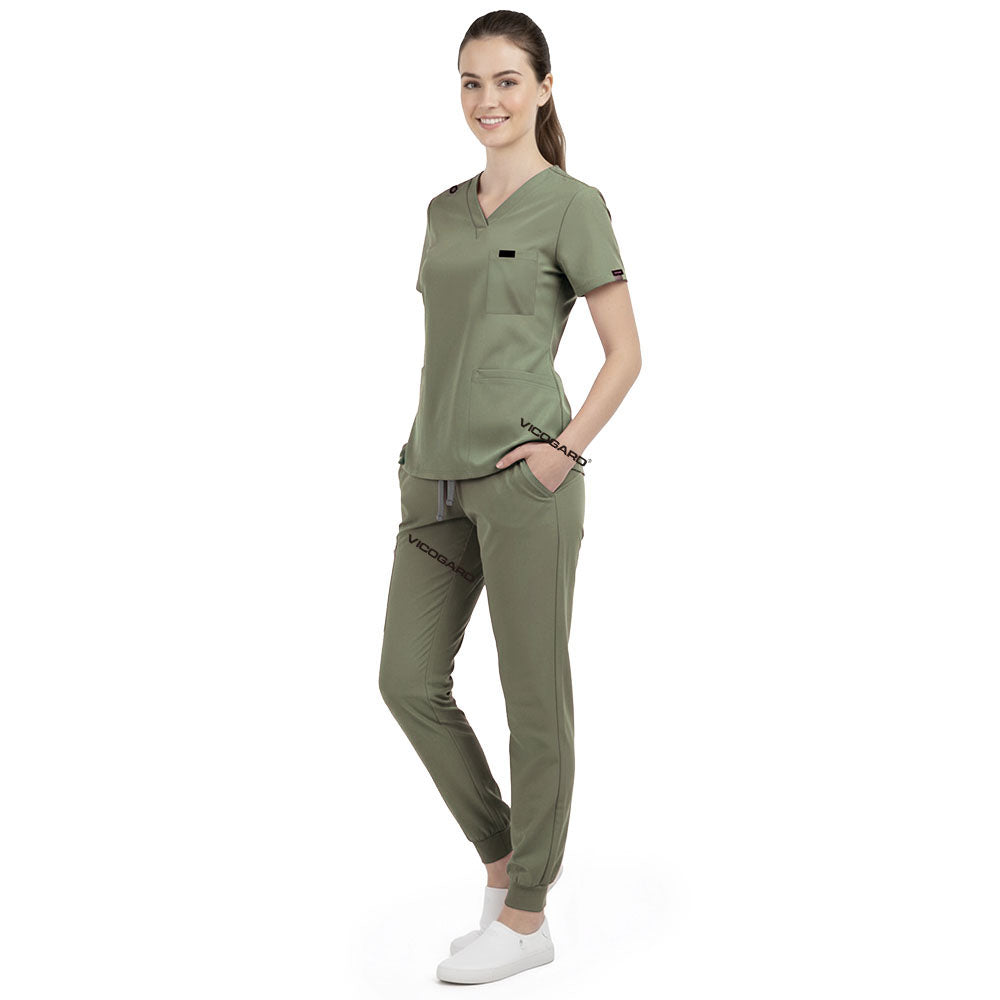 Front view of model with both hands in pockets, demonstrating relaxed fit of Fruit Green scrubs