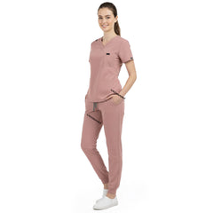 Front view of model with both hands in pockets, demonstrating relaxed fit of Pink scrubs