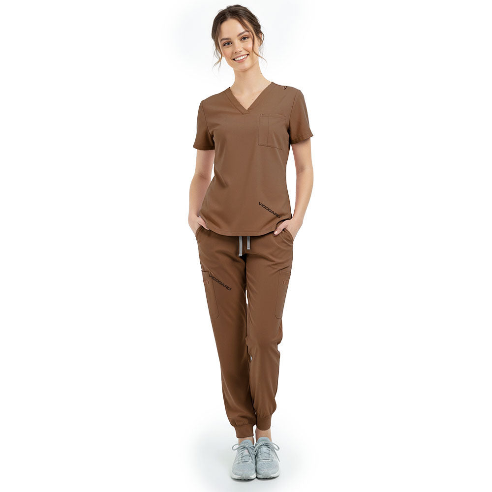 Front view of model with hands in pockets wearing Coffee scrubs, showing relaxed athletic fit