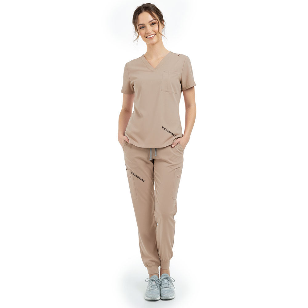 Front view of model with hands in pockets wearing Apricot scrubs, showing relaxed athletic fit