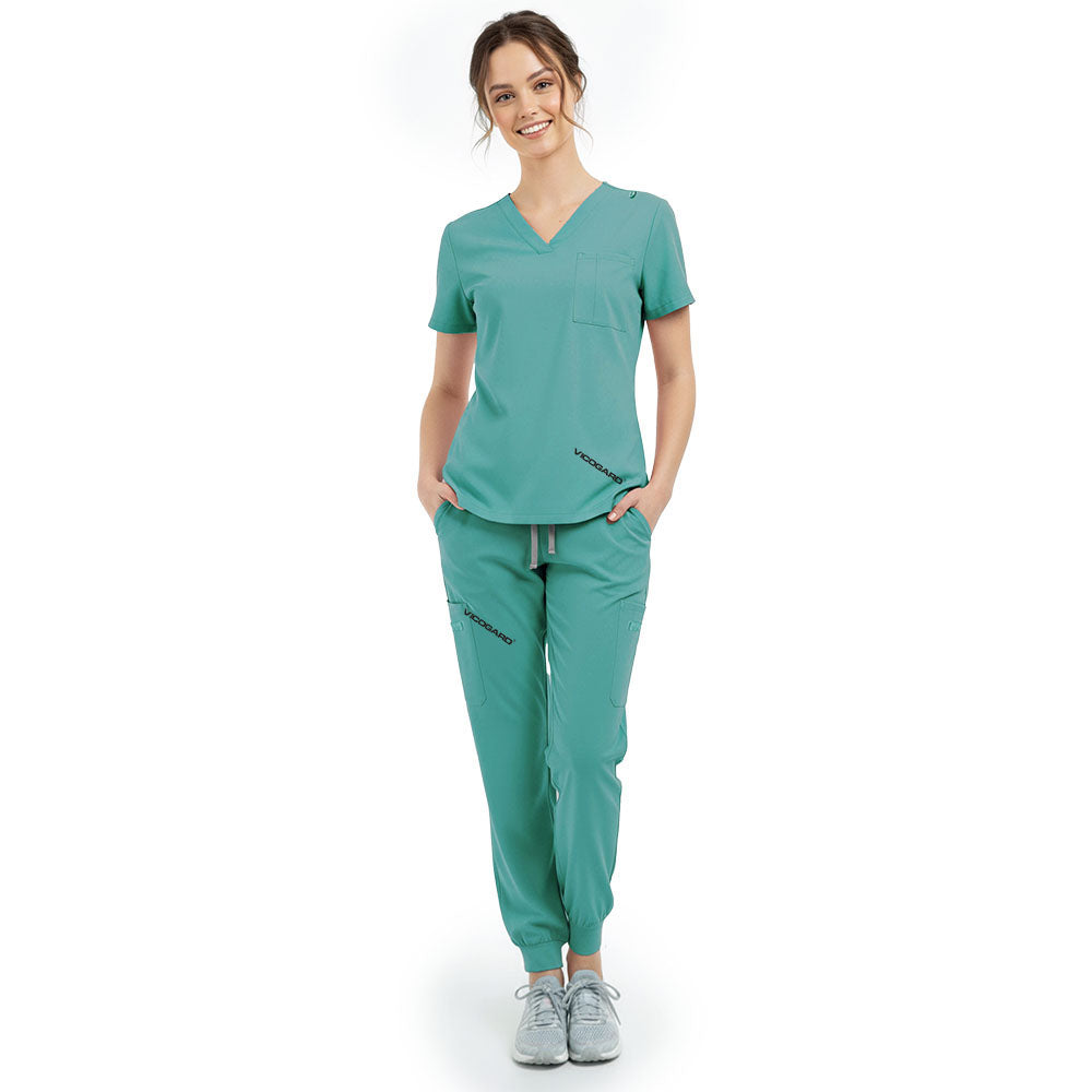 Front view of model with hands in pockets wearing Turquoise scrubs, showing relaxed athletic fit