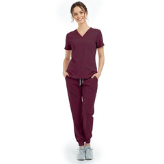 Front view of model with hands in pockets wearing Burgundy scrubs, showing relaxed athletic fit
